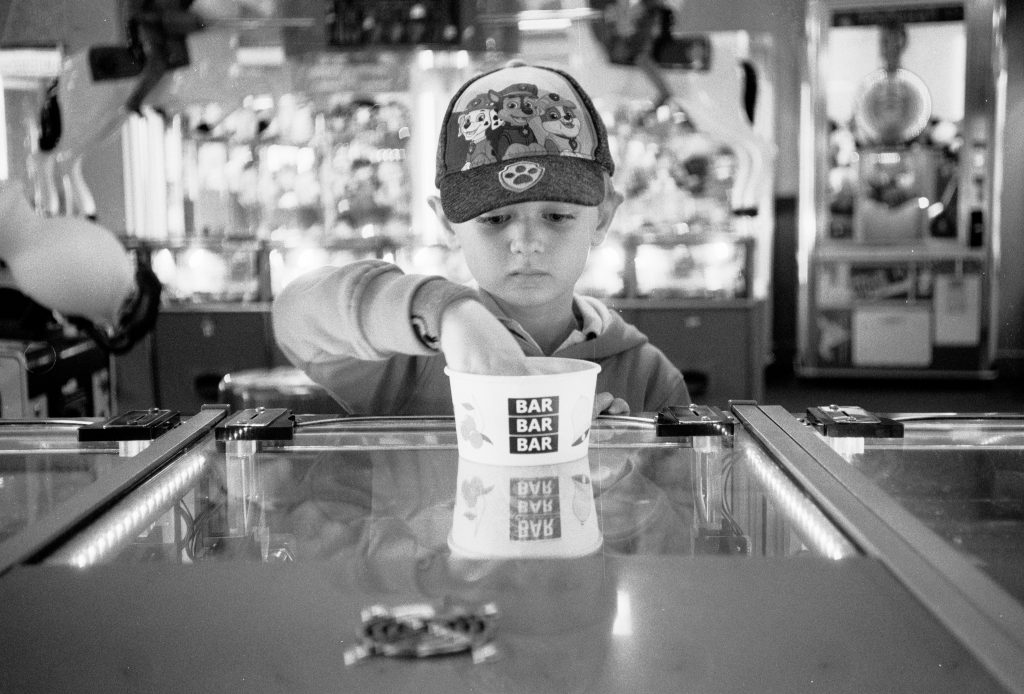 A black and white image of a young boy playing in an arcade